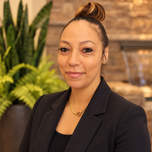 Woman with slight grin dressed in scoop neck top and business jacket.
