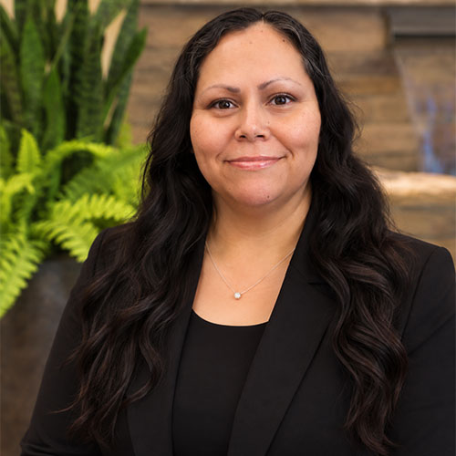 Smiling woman with long, dark hair dressed scoop neck top and business jacket