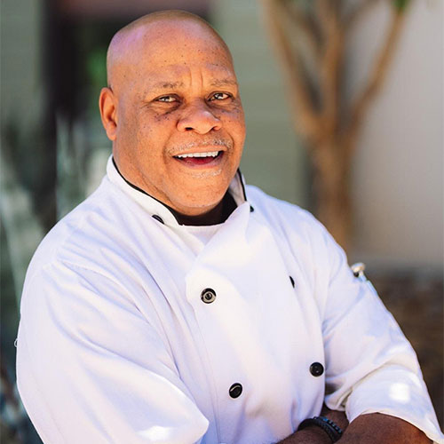 Smiling man with arms crossed wearing a chef's jacket