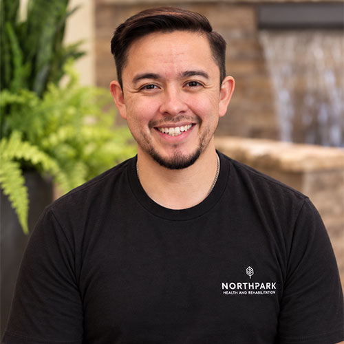 A smiling, dark-haired man wearing a t-shirt.
