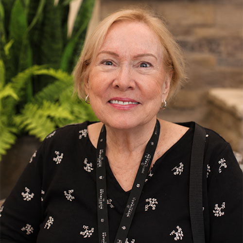 Smiling woman with her hair pulled back. She is wearing a V-neck top and a lanyard.