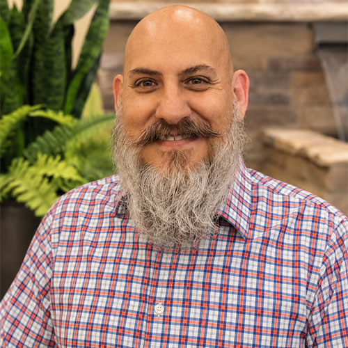 Smiling man with mustache and beard wearing plaid button down shirt